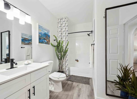 a bathroom with a white sink and toilet next to a white bathtub with a shower curtain