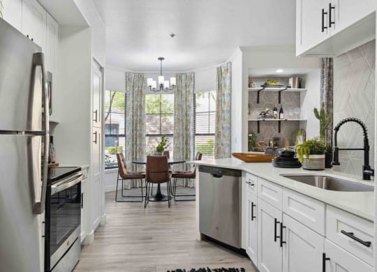 a kitchen with white cabinets and stainless steel appliances and a dining room with a table and chairs