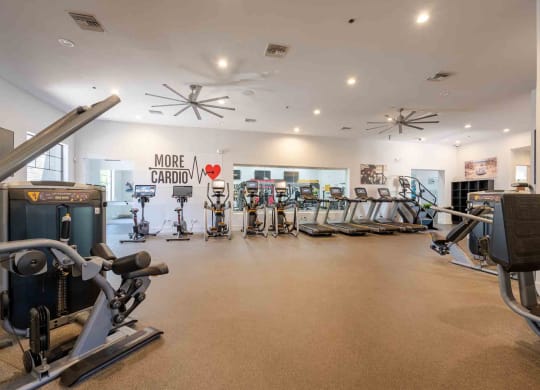 a spacious fitness center with cardio equipment and exercise machines