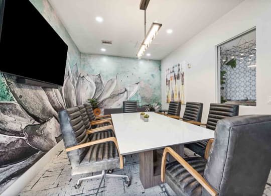 a meeting room with a white table and chairs and a large mural on the wall