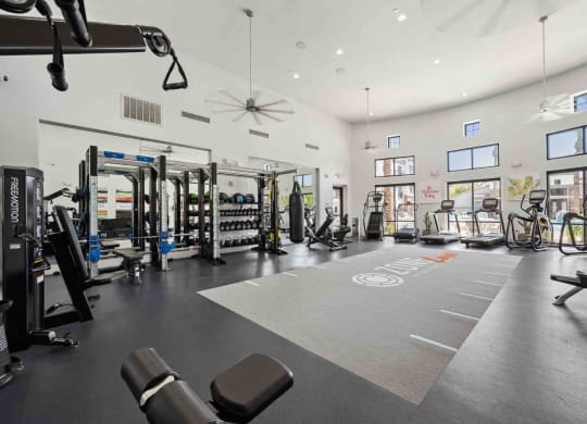 a spacious fitness center with cardio equipment and weights