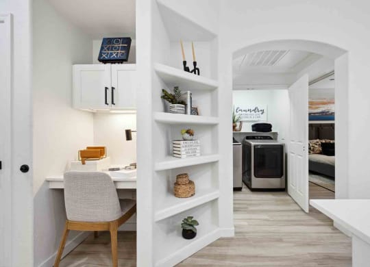 a home office with a white desk and chair next to a white bookshelf with a