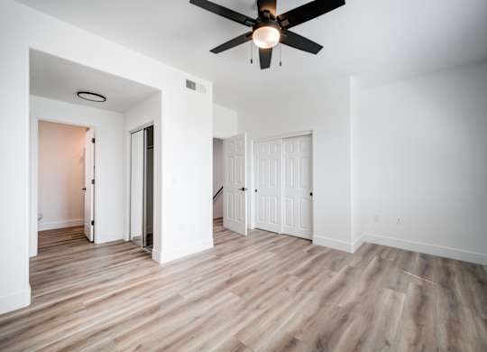 an empty living room with white walls and a ceiling fan