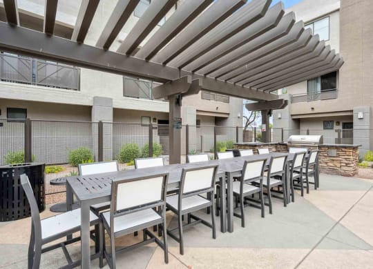 a patio with a long table and chairs and a fire pit in front of a building
