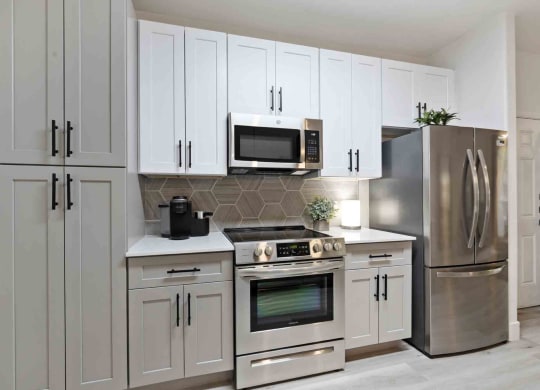 A kitchen with gray and white cabinets and stainless appliances at Zone Westgate, townhomes for rent in Glendale, AZ.