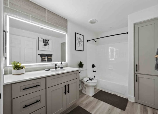 an all white bathroom with gray cabinets and a black shower curtain