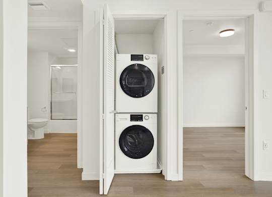 A white washer and dryer in a small room at 26FIFTY Apartments, Berkeley 94704