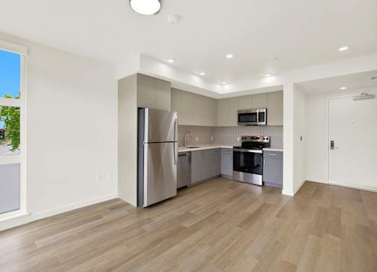 A modern kitchen with a refrigerator, oven, and microwave at 26FIFTY Apartments, Berkeley