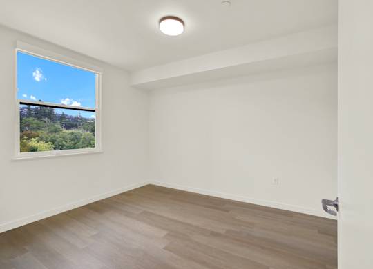 A room with a large window and wooden flooring at 26FIFTY Apartments, Berkeley