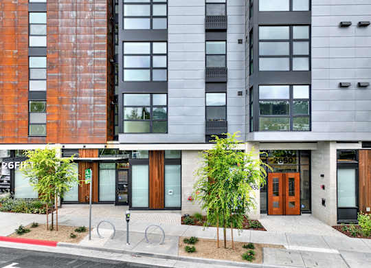 A modern building with a red brick facade and a grey facade with windows at 26FIFTY Apartments, Berkeley 94704