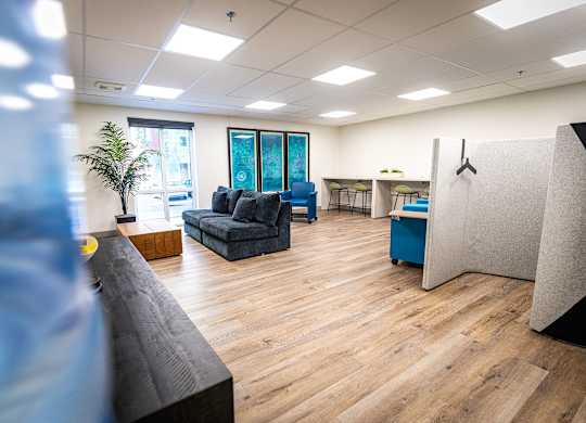 a room with couches and a desk in a office with wood floors