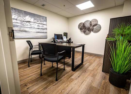 an office with a desk and chairs and a painting on the wall