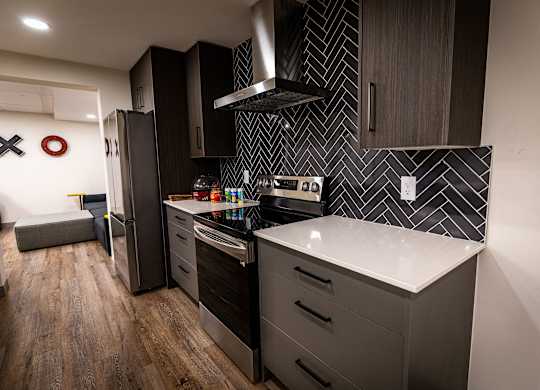 a kitchen with black cabinets and a white counter top and a refrigerator