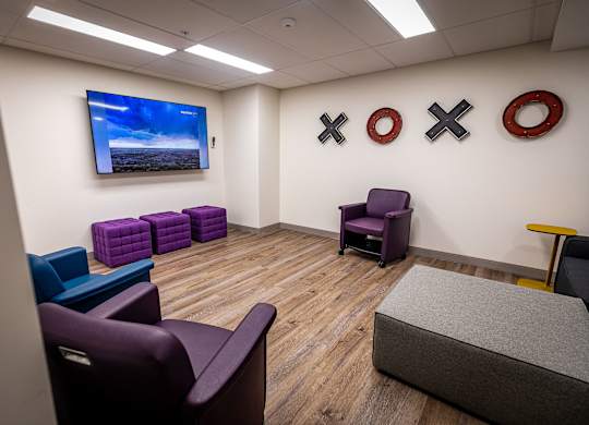a waiting room with purple chairs and a tv