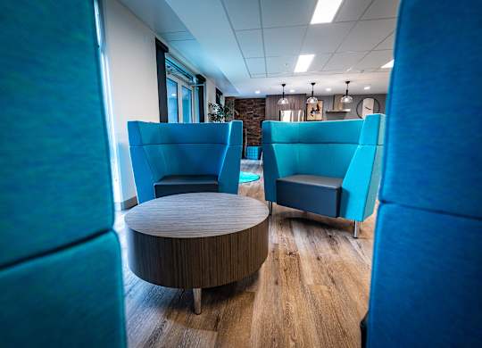 a lounge area with blue chairs and a coffee table