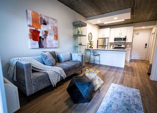 a living room with a couch and a table in front of a kitchen