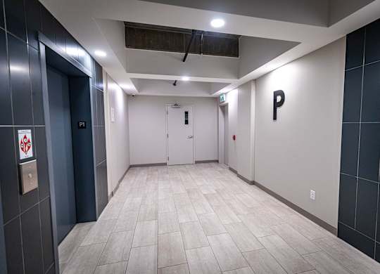 a hallway with white walls and tile floors and two doors