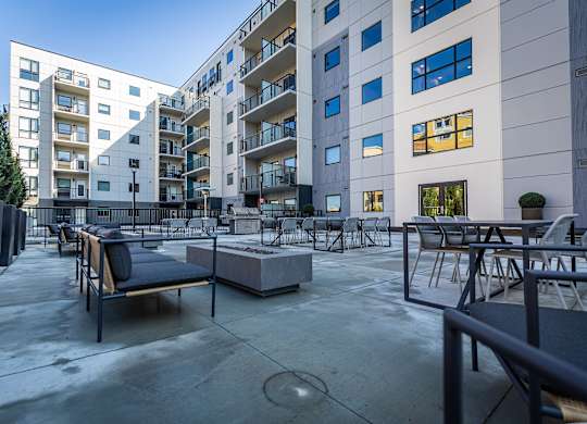 a large patio with tables and chairs in front of an apartment building