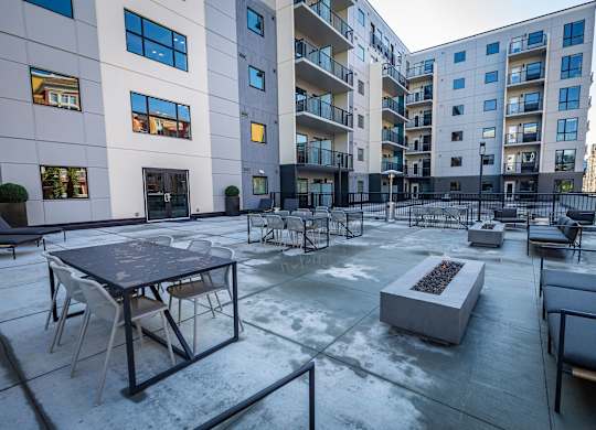 an open courtyard with tables and chairs in front of an apartment building