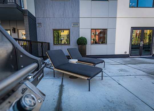 two lounge chairs on the sidewalk in front of a building