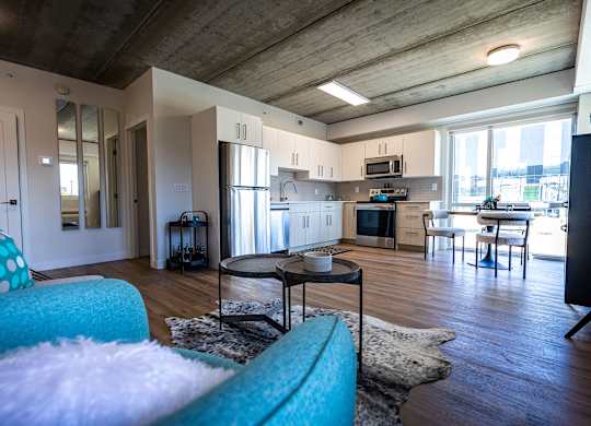 a living room with a couch and a table in front of a kitchen