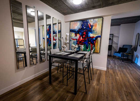a dining room with a table and chairs and a painting on the wall
