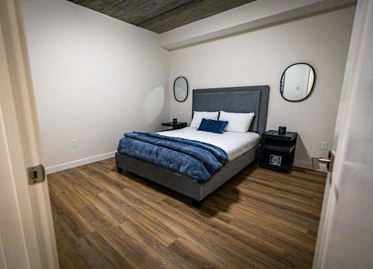 a bedroom with a bed in a room with wooden floors