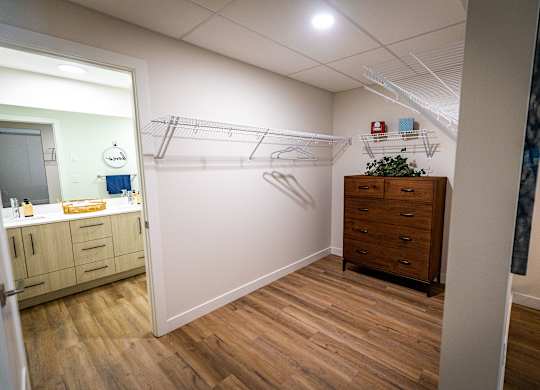 a walk in closet in a bathroom with a mirror and a dresser