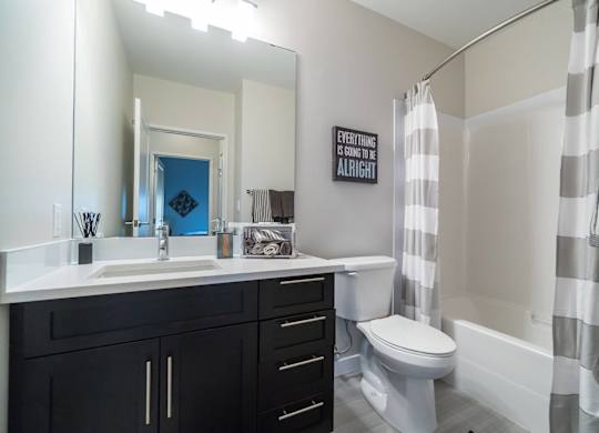 A bathroom with a white sink and black cabinets.