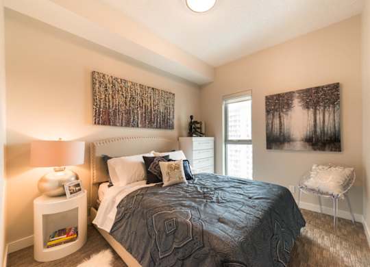 A bedroom with a bed, nightstand, and two pictures on the wall.