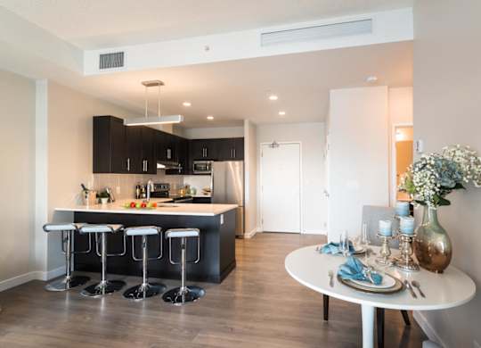A modern kitchen with a bar area and a dining table set for two.