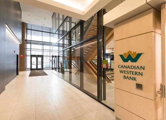 The lobby of the Canadian Western Bank building features a staircase and glass walls.