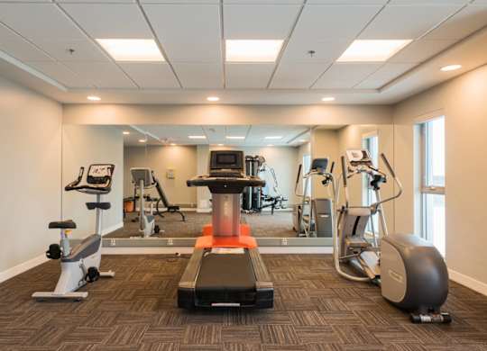 A gym with a variety of equipment including a treadmill, weights, and a stationary bike.