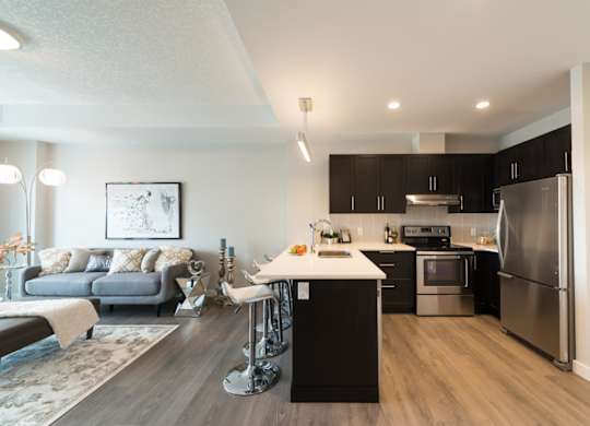 A modern kitchen with dark wood cabinets and stainless steel appliances.