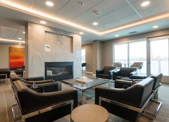 A modern living room with a fireplace and black leather furniture.