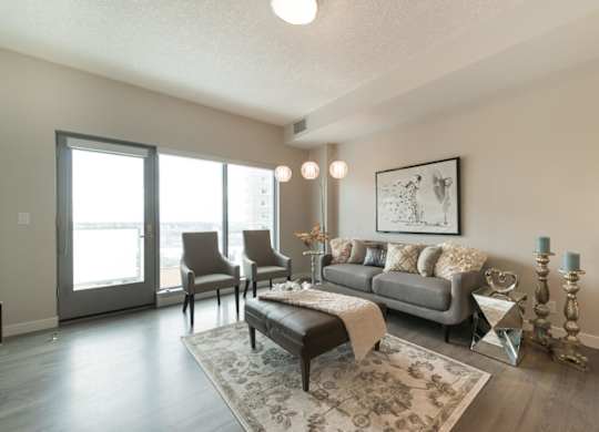 A living room with a grey couch, a coffee table, and a large window.