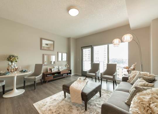 A living room with a grey couch, a white table, and a large window.