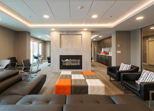 A modern living room with a fireplace and black leather furniture.