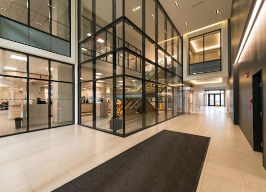 A hallway with a black carpet and glass walls.