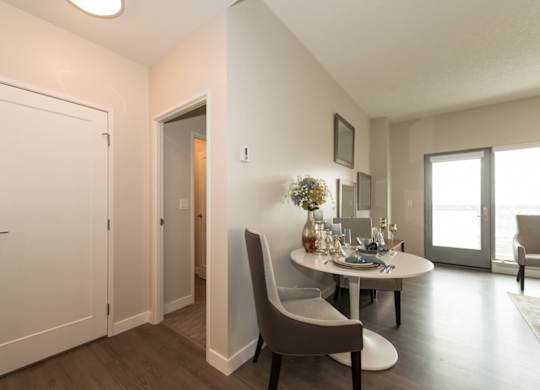 A dining room with a table set for two and a couch.