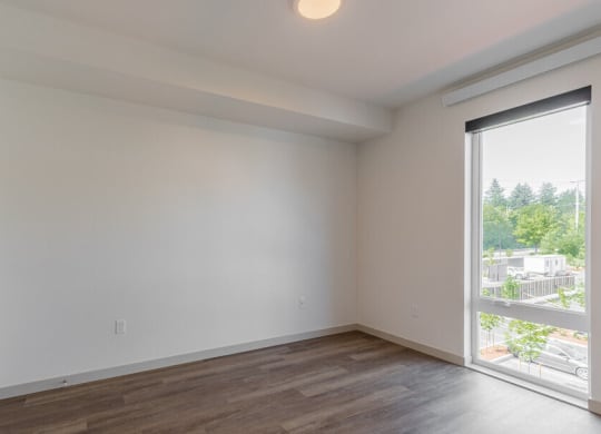 a bedroom with a large window and hardwood floors