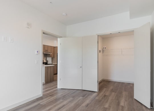 an empty room with a kitchen in the background