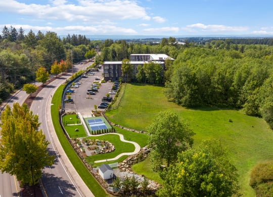 an aerial view of a parking lot and a park with trees
