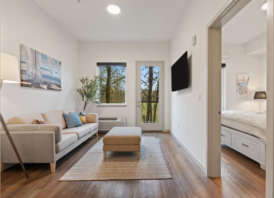 a living room with a couch and a chair and a door to a bedroom