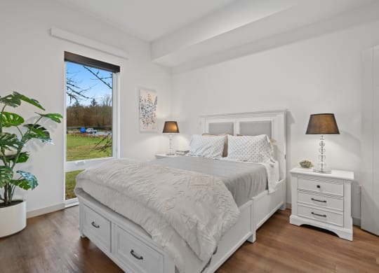 a white bedroom with a bed and a large window