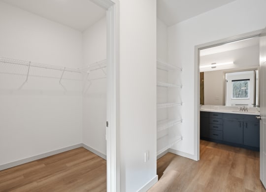 a bedroom with a closet and a bathroom with a sink and a mirror