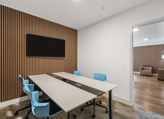 a conference room with a table and chairs and a tv on the wall