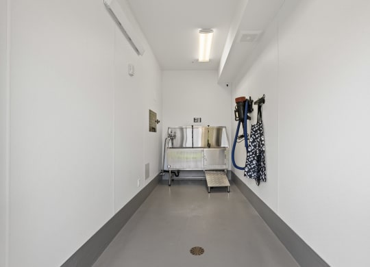 a long white hallway with white walls and a metal cart with hoses in it