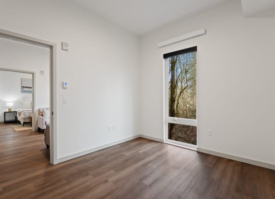 a living room with white walls and a large window and wooden floors