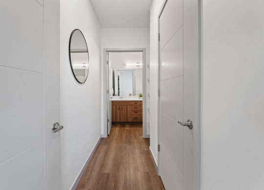 a hallway with white walls and wooden floors and a mirror